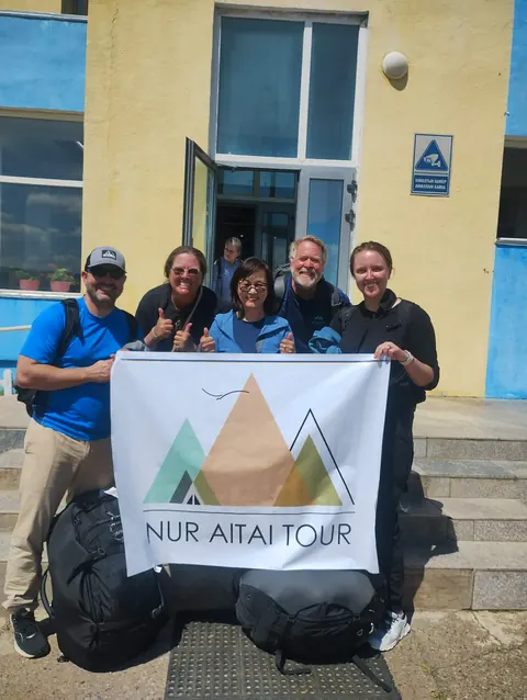 Travelers with the Nur Altai Tour banner