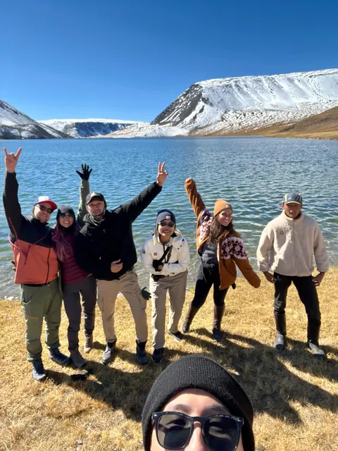 Group waving by a mountain lake