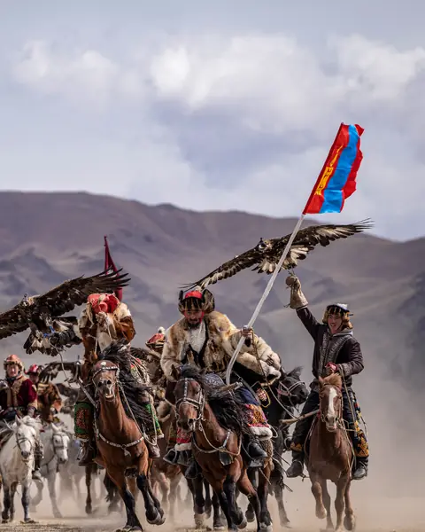 Kazakh eagle hunters riding with golden eagles in the Altai