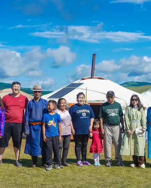 Mongolian family in traditional deel in front of their ger