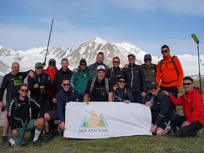 Nur Altai Tour hiking group with the company banner below snowy Altai peaks