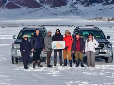 Travellers with Nur Altai Tour vehicles on a frozen lake in winter