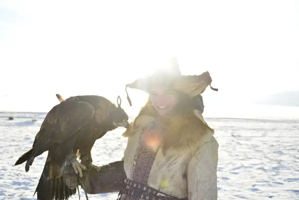 Eagle hunter with her golden eagle in the winter snow