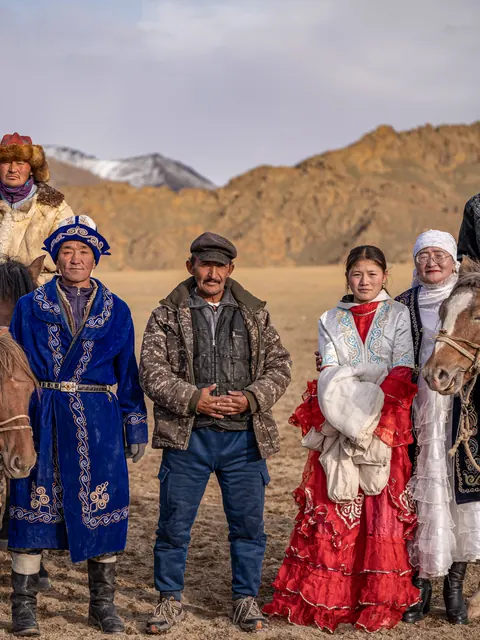 Kazakh eagle hunter family with horses in the Altai mountains