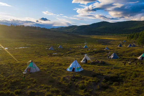 Teepees scattered across a golden taiga valley