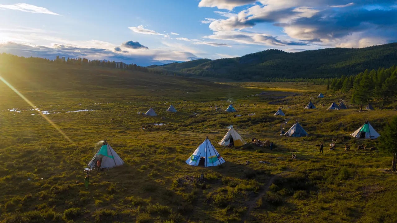 Reindeer herder teepees in a taiga valley at sunset, northern Mongolia
