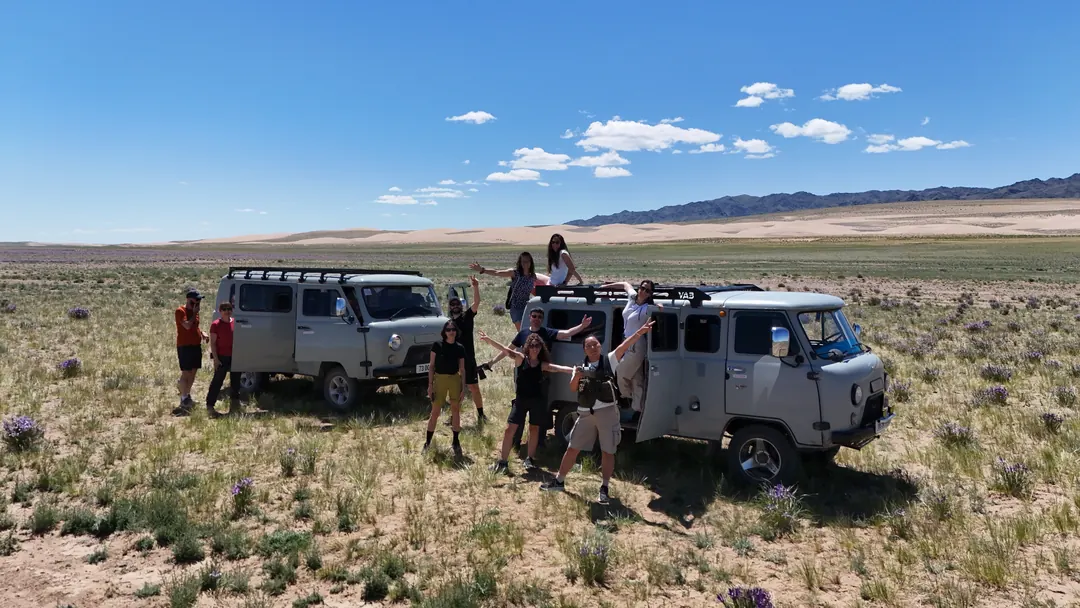 Travellers waving from two UAZ vans on the Gobi steppe